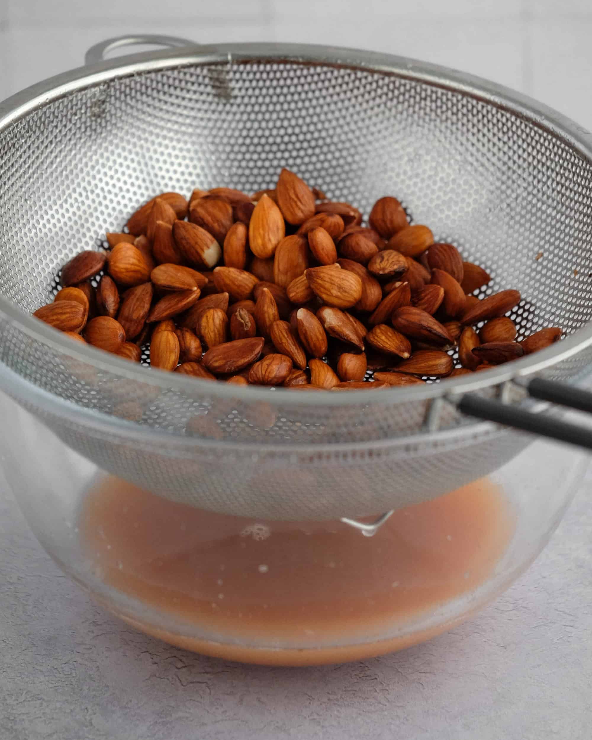 almonds in sieve over a glass bowl 